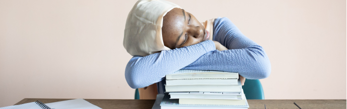girl at desk sleeping on a stack of books